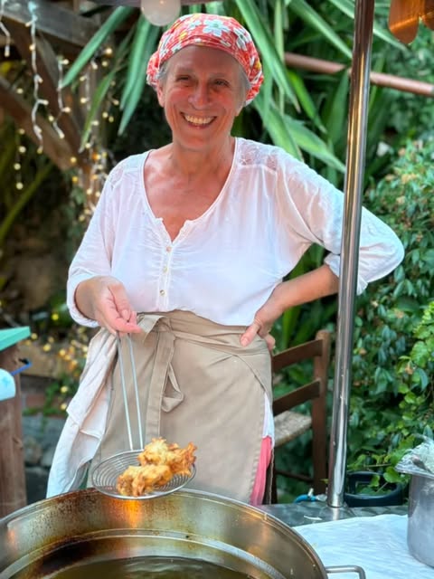 Elvira solleva i frisciöi appena fritti dalla padella, nel dehors del ristorante